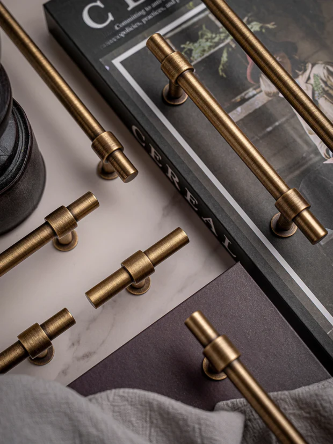 Set of gold cabinet handles on a surface with a magazine in the background