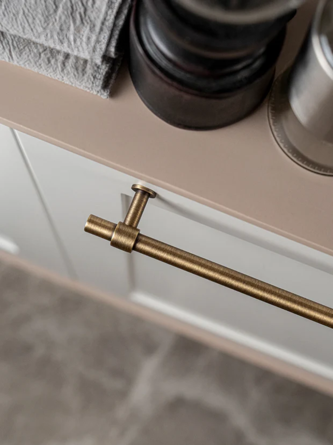 Close-up of a gold handle on a cabinet with a neutral background