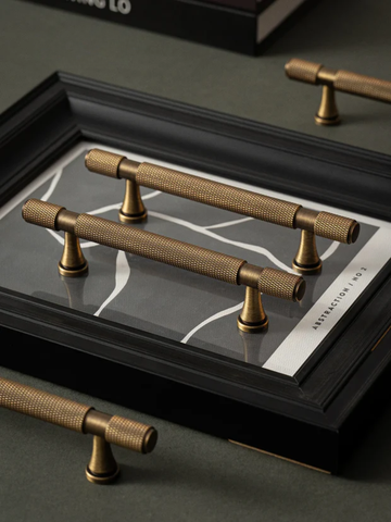 Brass cabinet handles on a dark surface with a branded box in the background