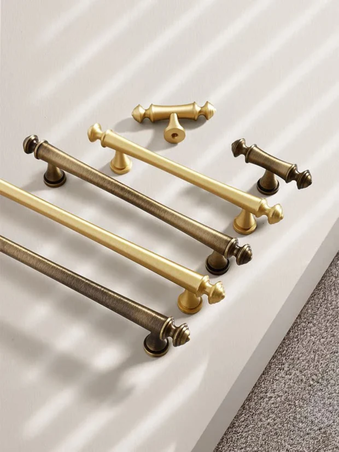 Set of gold and bronze cabinet handles on a white surface