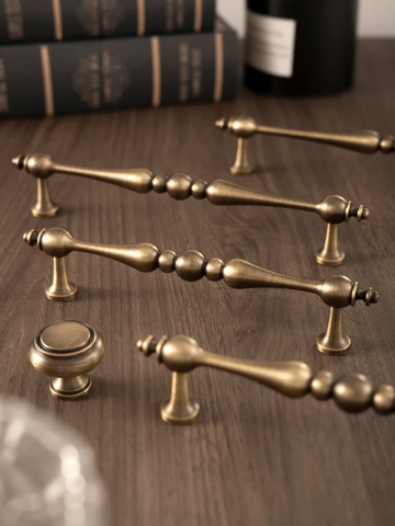 Set of vintage-style brass cabinet handles on a wooden surface
