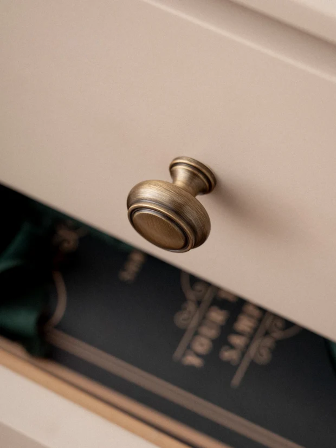 Close-up of a brass cabinet knob on a white cabinet with a blurred background
