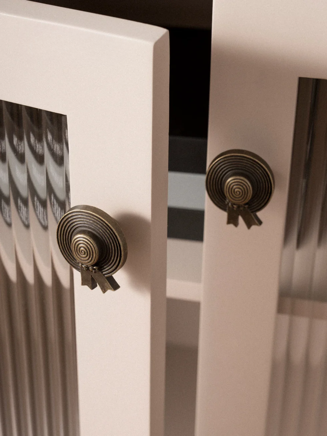 Close-up of decorative metal knobs on a white cabinet with a blurred background.