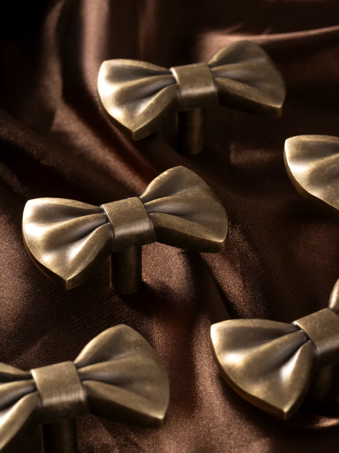 Bronze bow-shaped objects on a brown fabric background