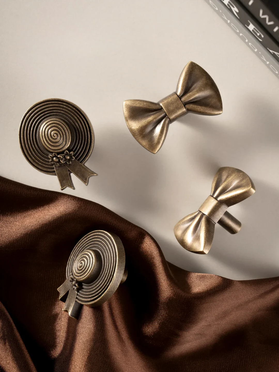 Bronze bow-shaped cufflinks on a brown fabric surface