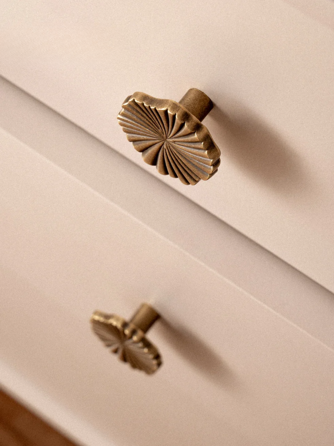 Close-up of a beige cabinet with decorative brass handles