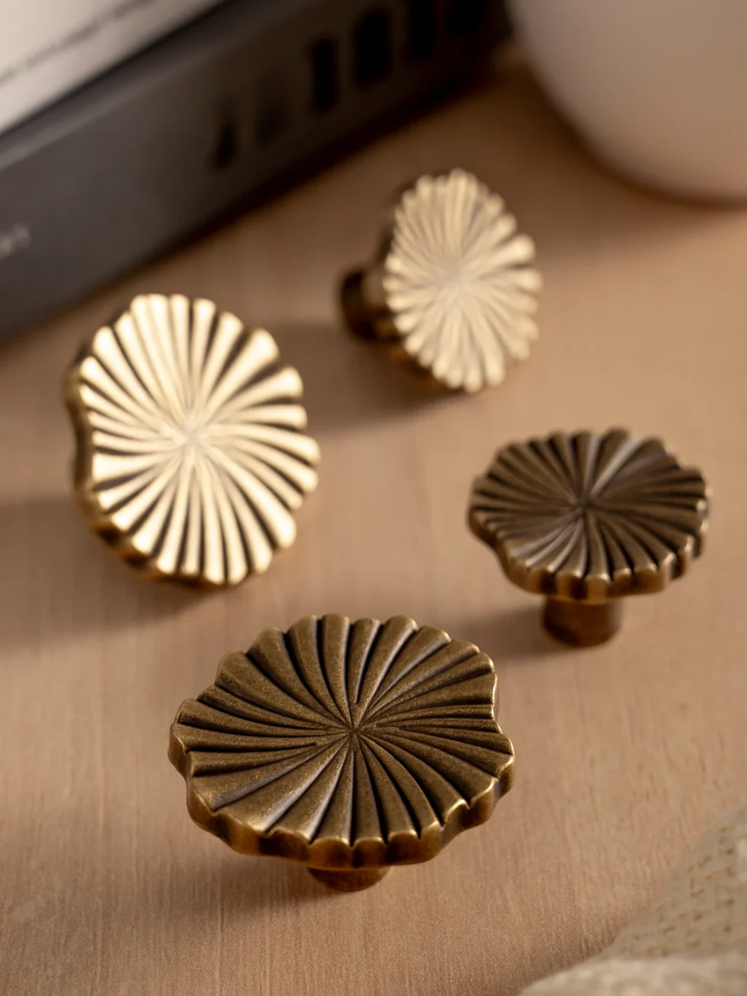 Set of four decorative brass cabinet knobs on a wooden surface.