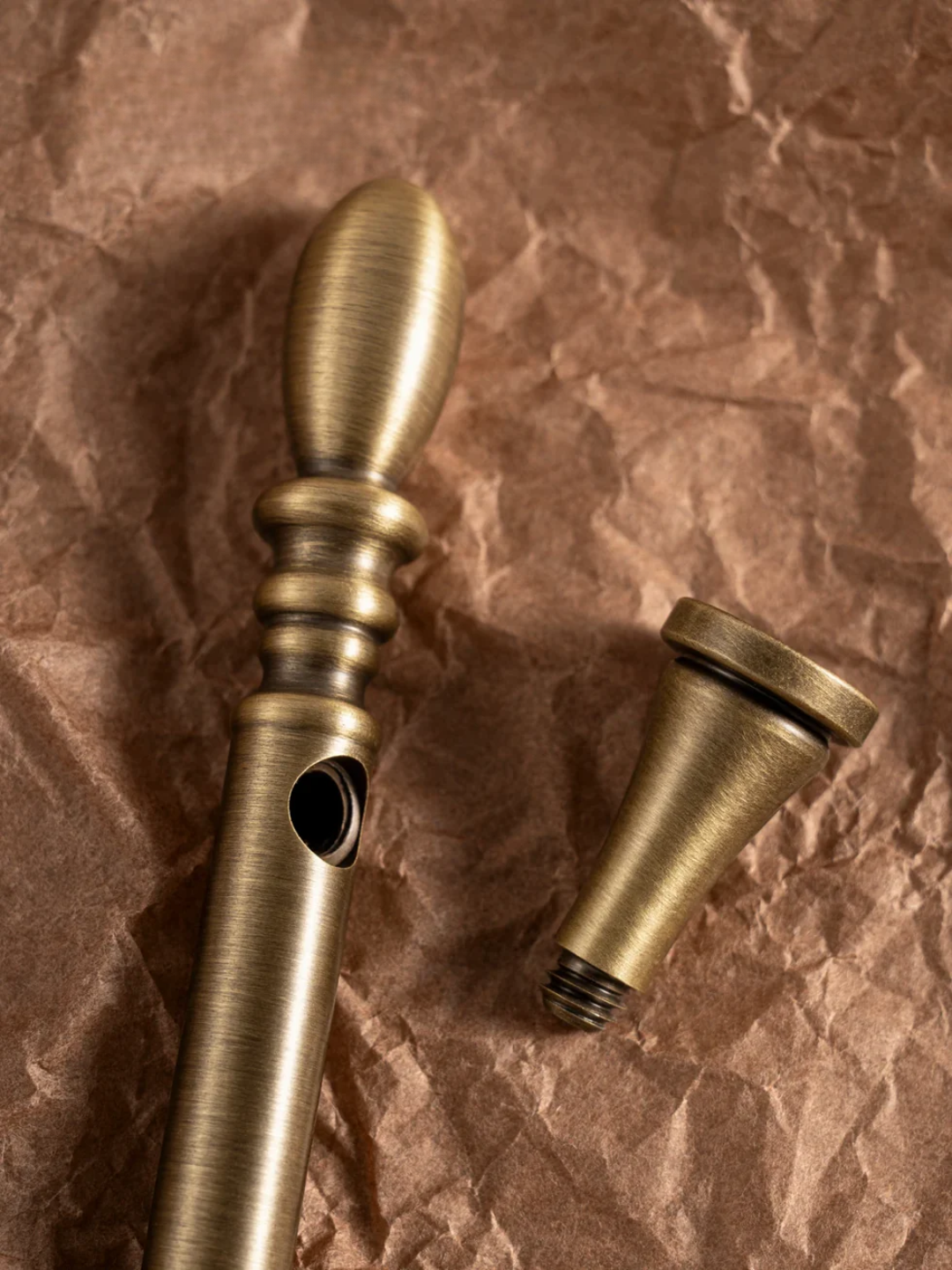 Two brass curtain rods on a textured brown surface