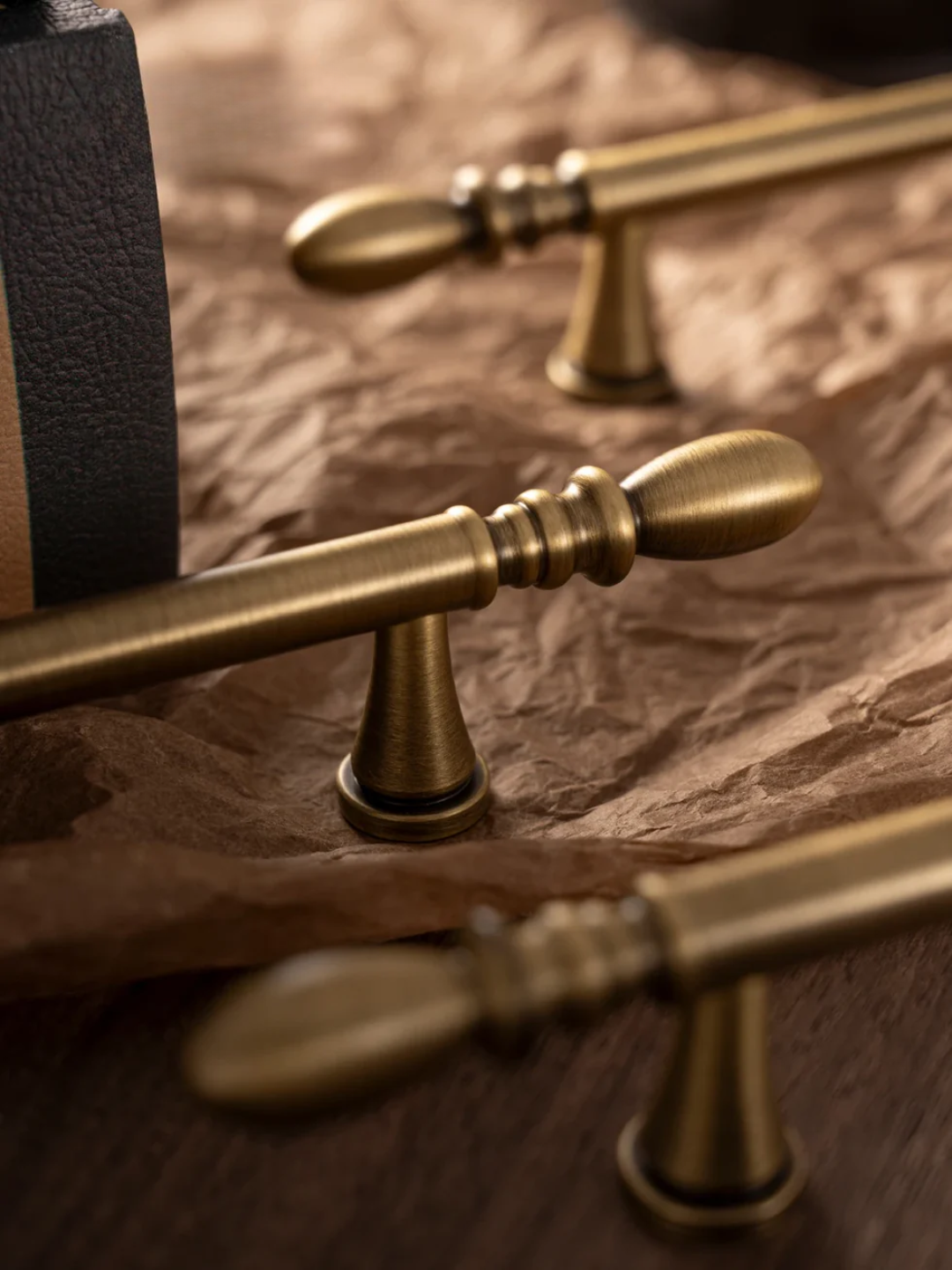 Close-up of gold curtain rods with decorative finials on a textured surface