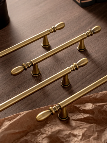 Set of gold cabinet handles on a wooden surface
