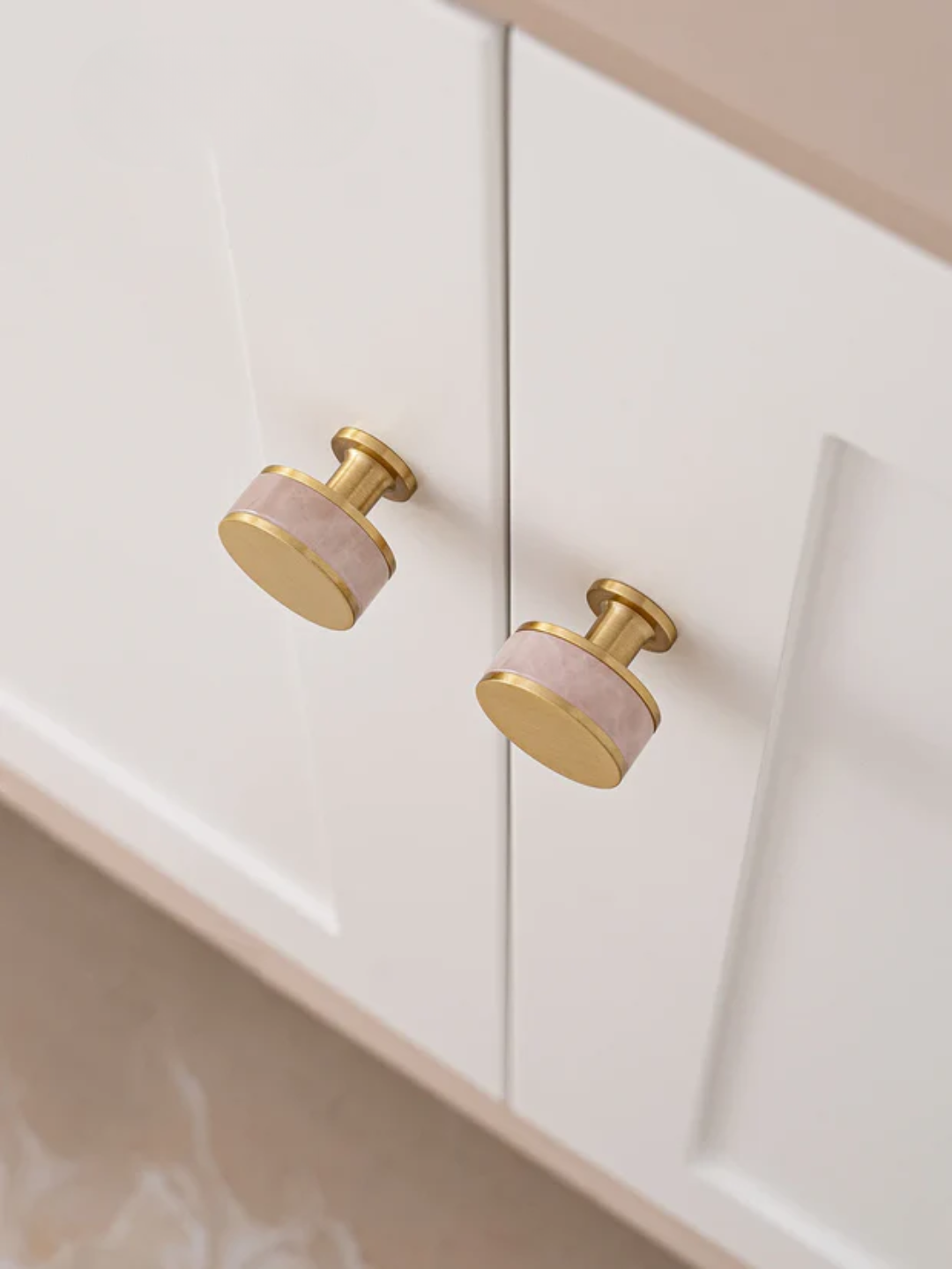Close-up of a cabinet with pink and gold knobs on a white background