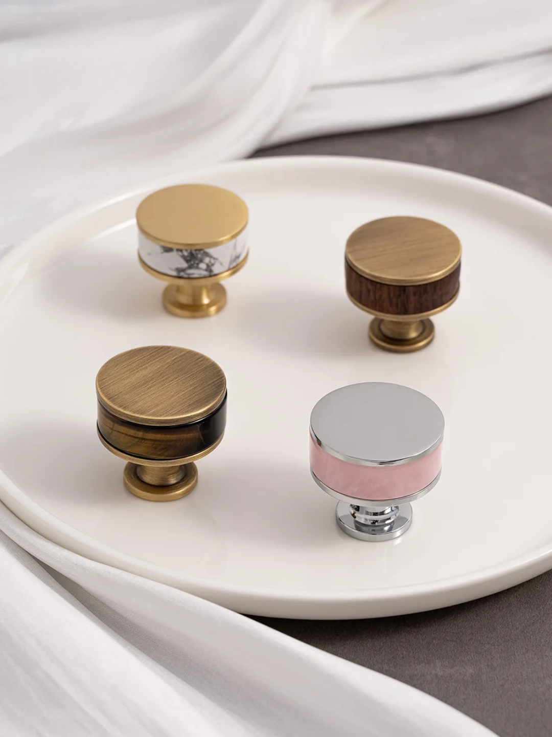 Set of four cabinet knobs with different finishes on a white plate.