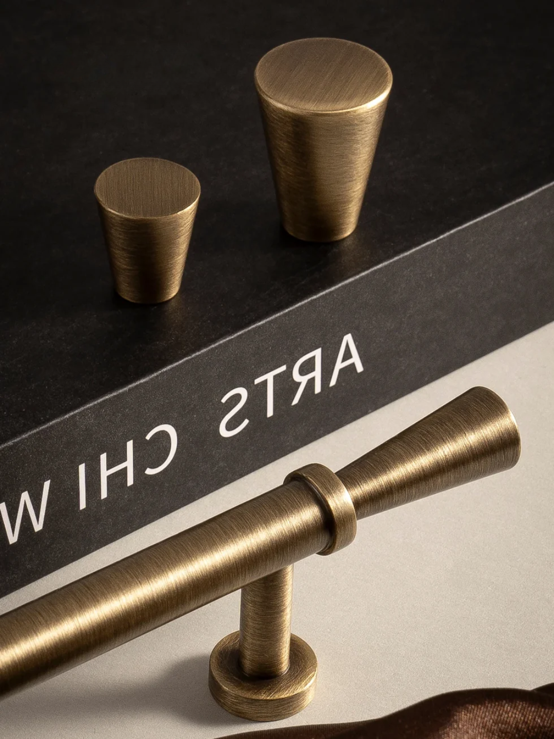 Brass cabinet handles on a dark surface with 'Arts & Crafts' branding.