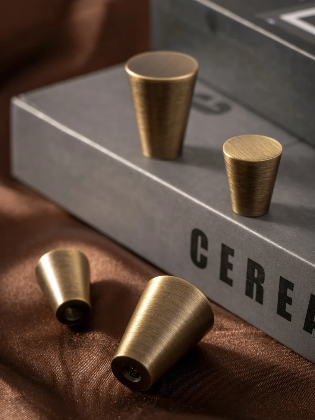 Three brass cups on a gray surface with 'CEREA' branding.
