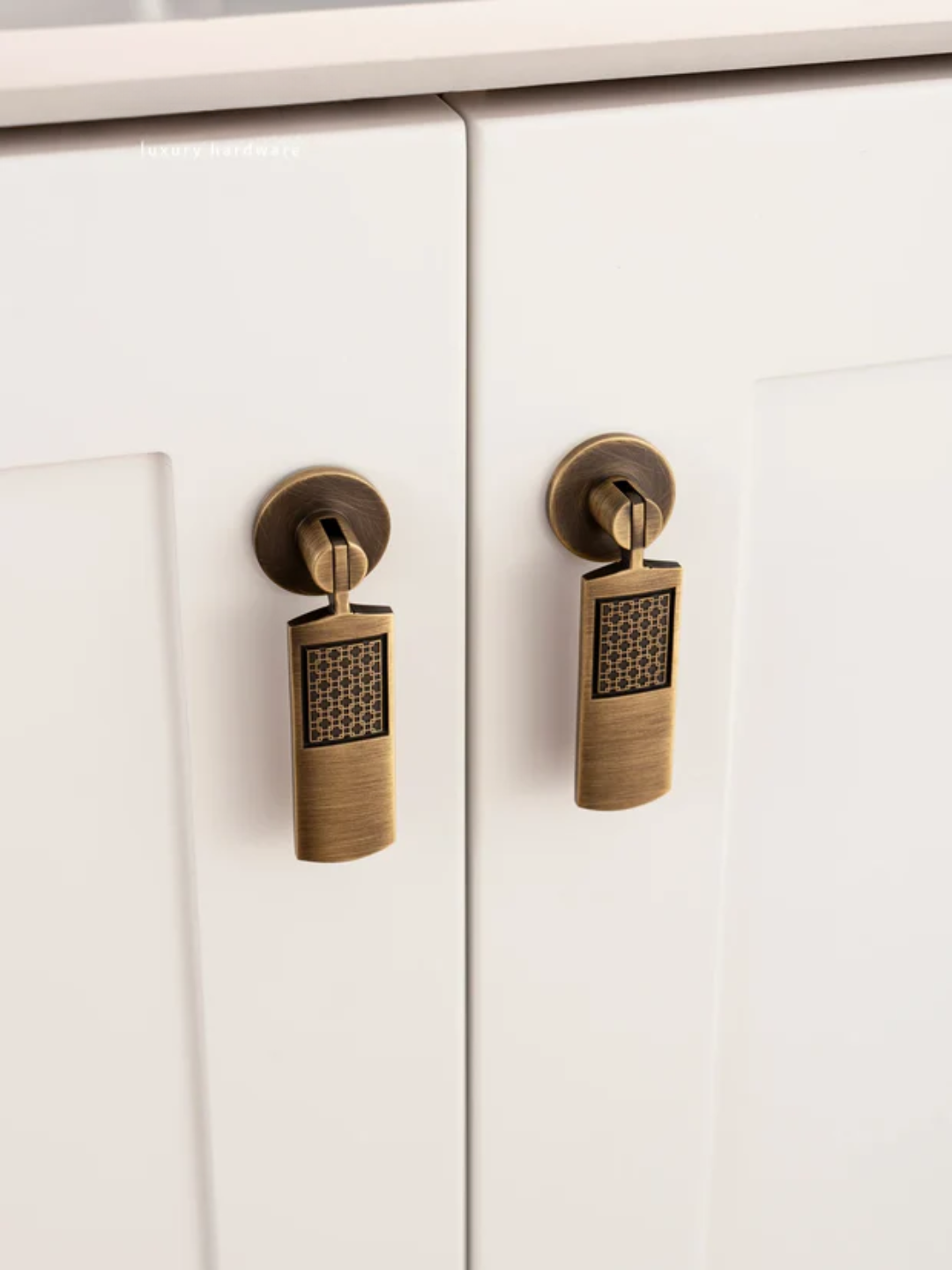 Close-up of white cabinet doors with bronze handles on a light background