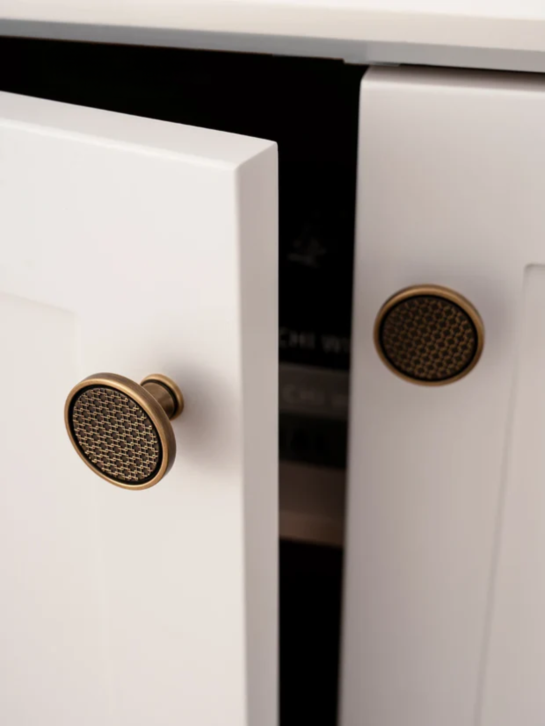 Close-up of a white cabinet with bronze knobs