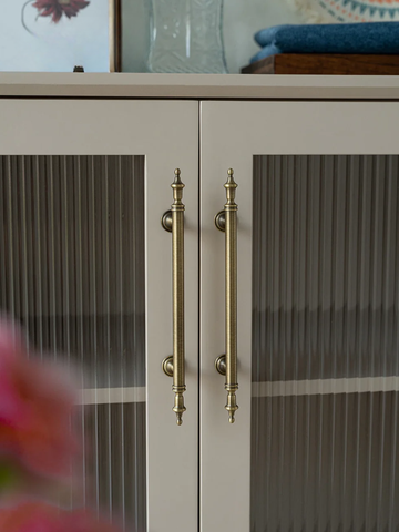 Cabinet with gold handles and glass doors, blurred background