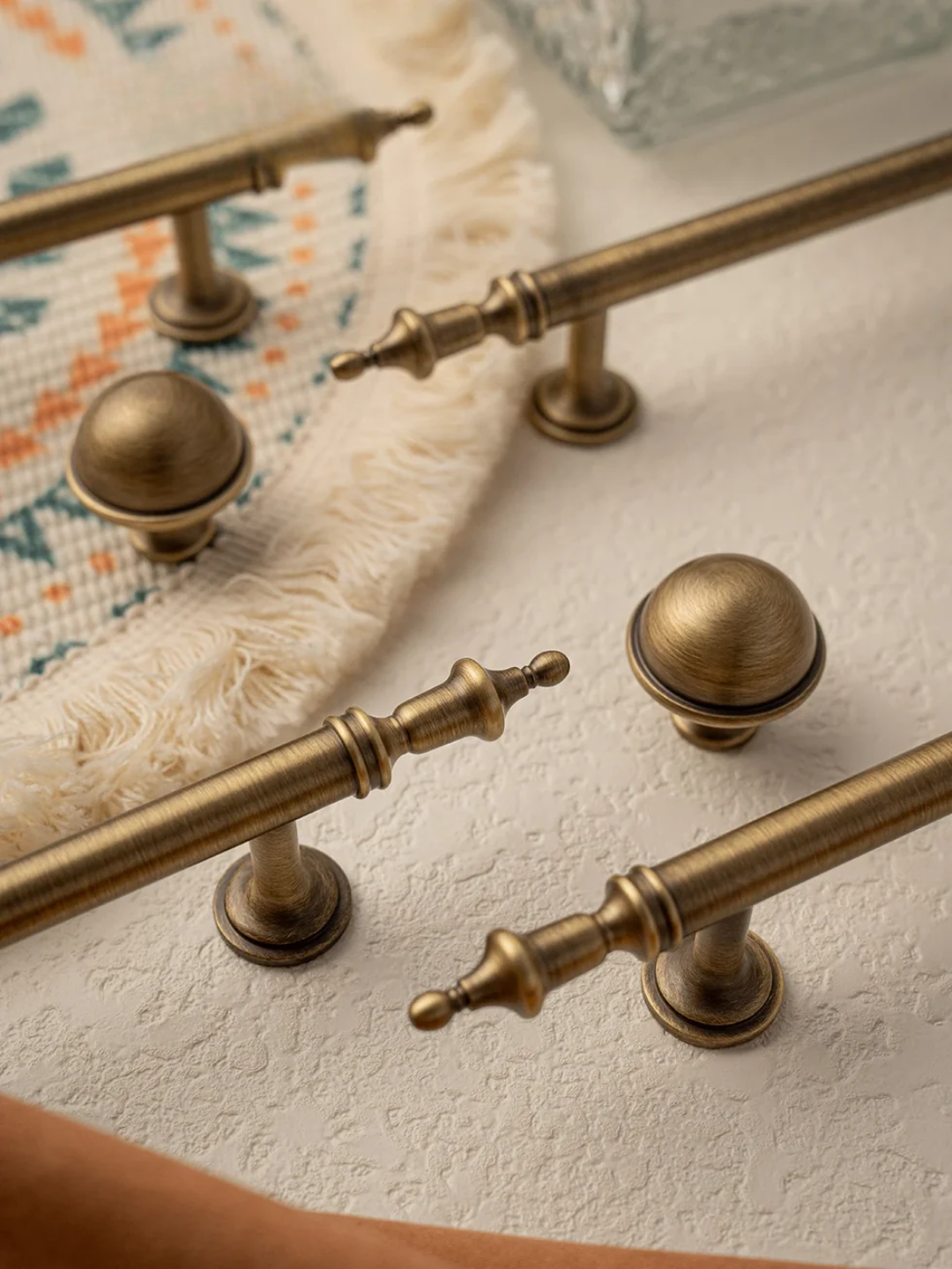 Close-up of brass cabinet handles and knobs on a textured surface.