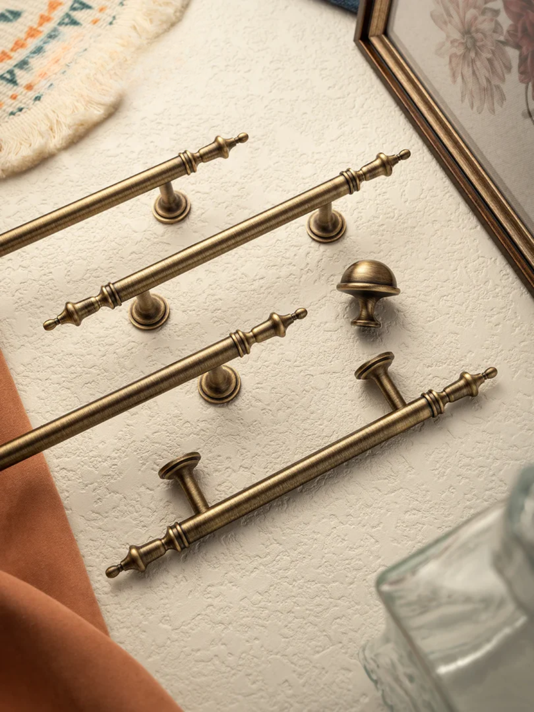 Set of gold cabinet handles and knobs on a textured surface