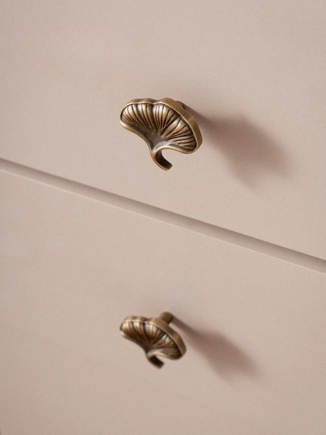 Brass cabinet knobs on a beige drawer