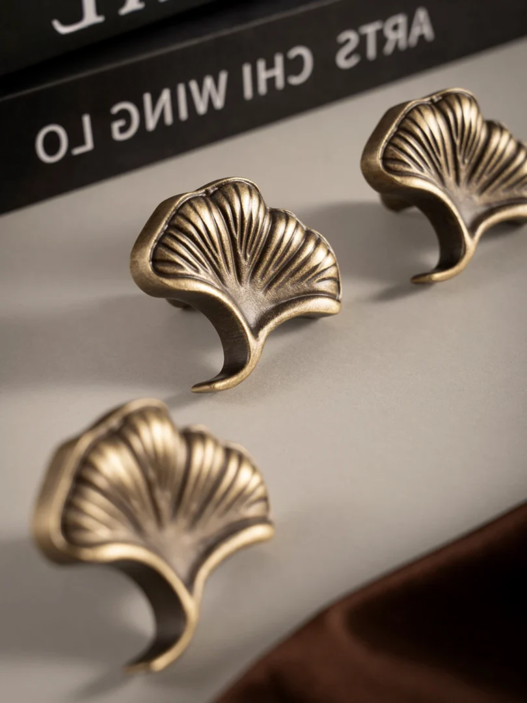 Four gold leaf-shaped earrings on a brown fabric background