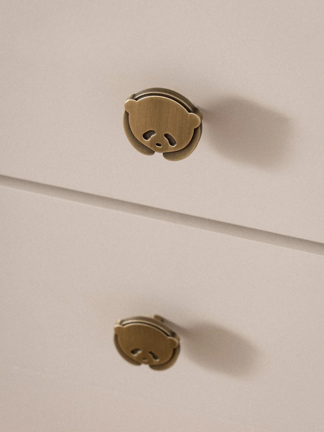 Two gold panda-shaped buttons on a beige background