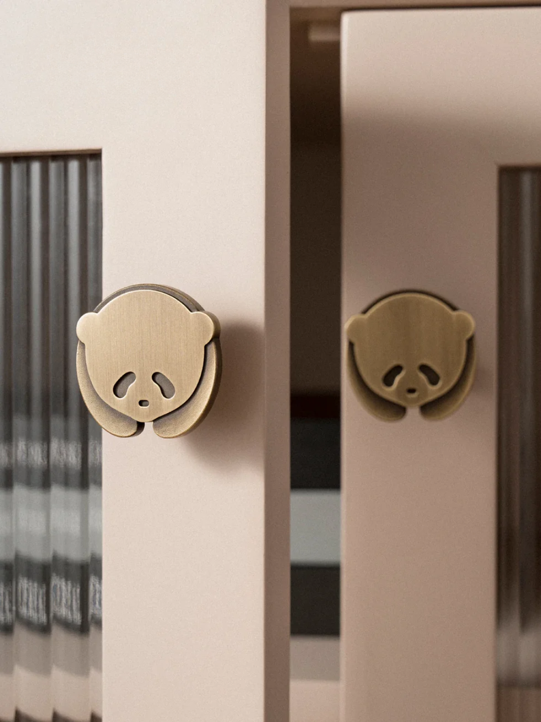 Brass monkey-shaped door handles on a wooden cabinet.