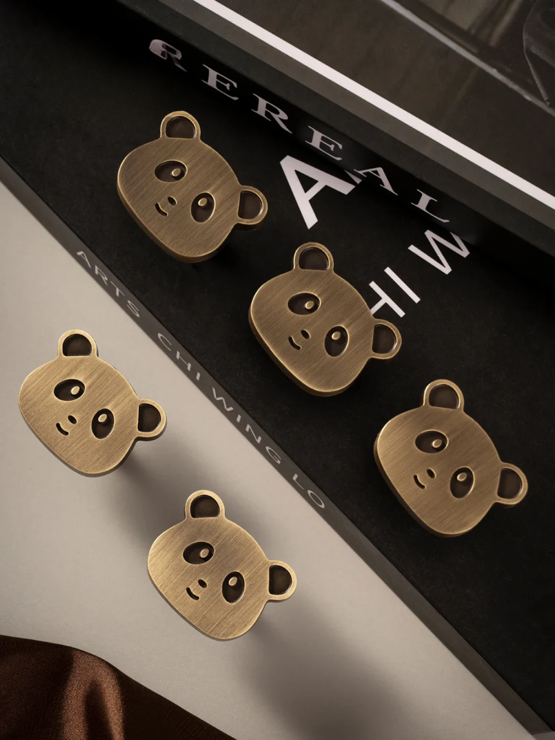 Bronze panda-shaped earrings on a black background with 'Pereau' branding.