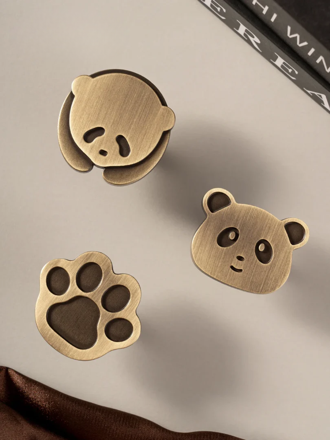 Bronze panda-shaped earrings on a neutral background