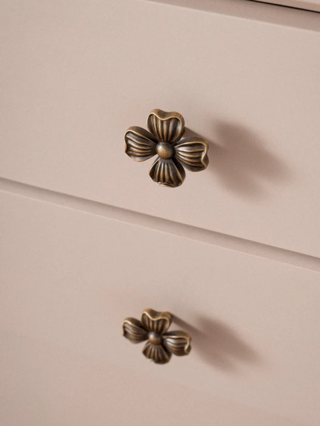 Close-up of a beige cabinet with decorative bronze handles.