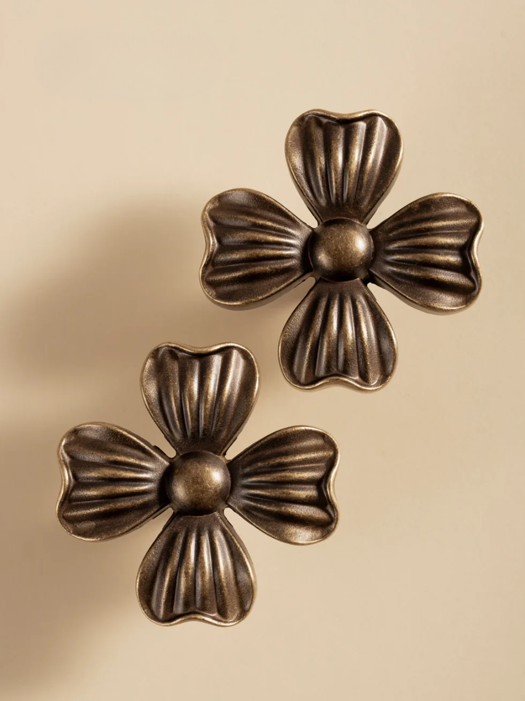 Two bronze floral designs on a beige background
