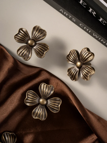Bronze floral earrings on a brown fabric background