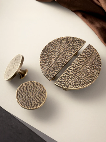 Set of three bronze-colored knobs on a white surface