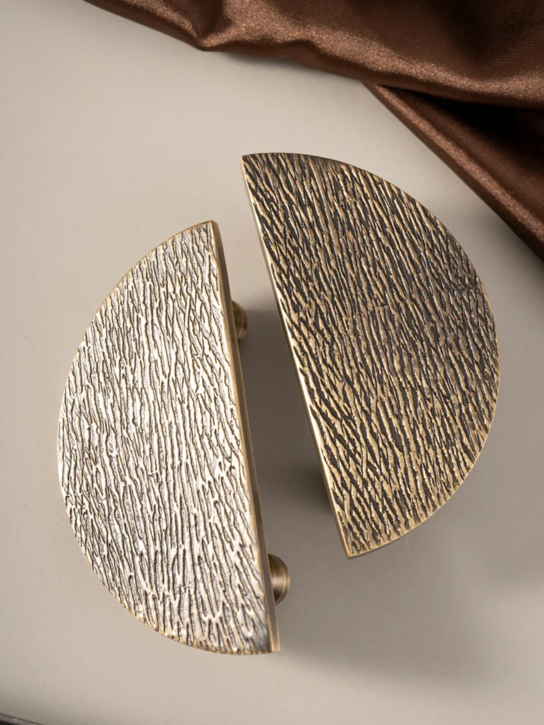 Pair of textured gold earrings on a neutral background