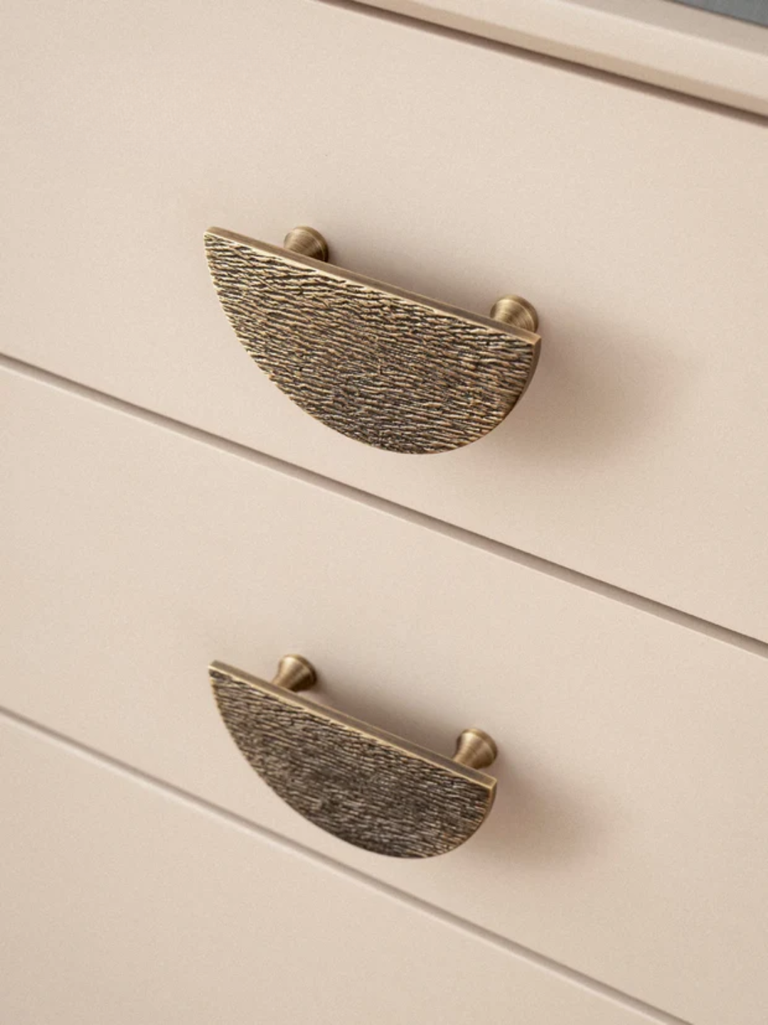 Brass cabinet handles on a beige drawer