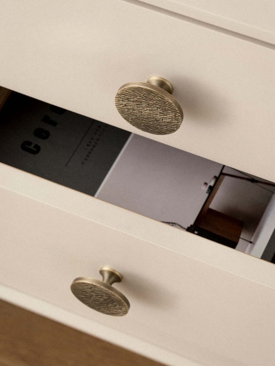 Close-up of a white drawer with brass knobs.