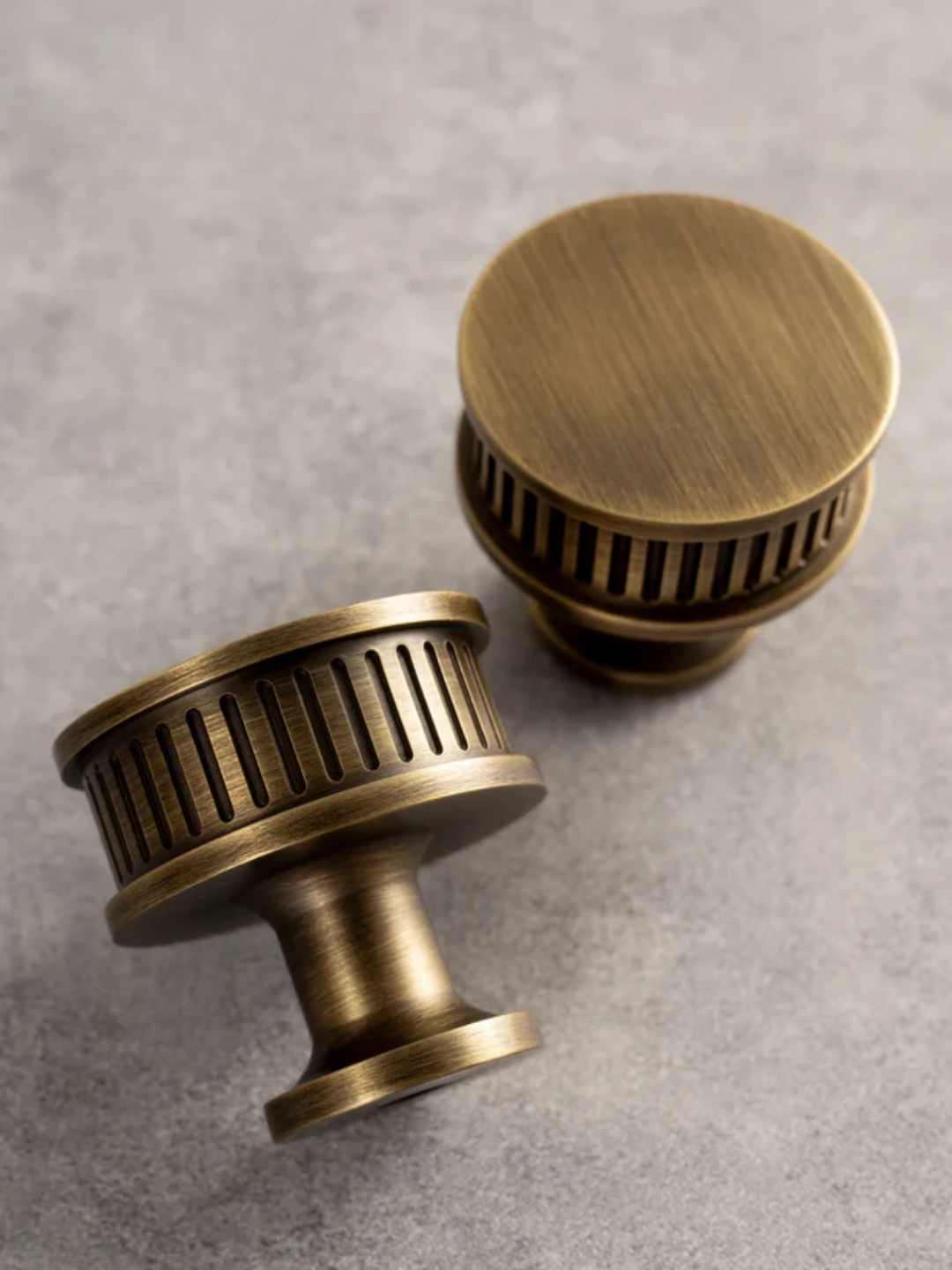 Two brass cabinet knobs on a gray surface with 'Santaya' branding.