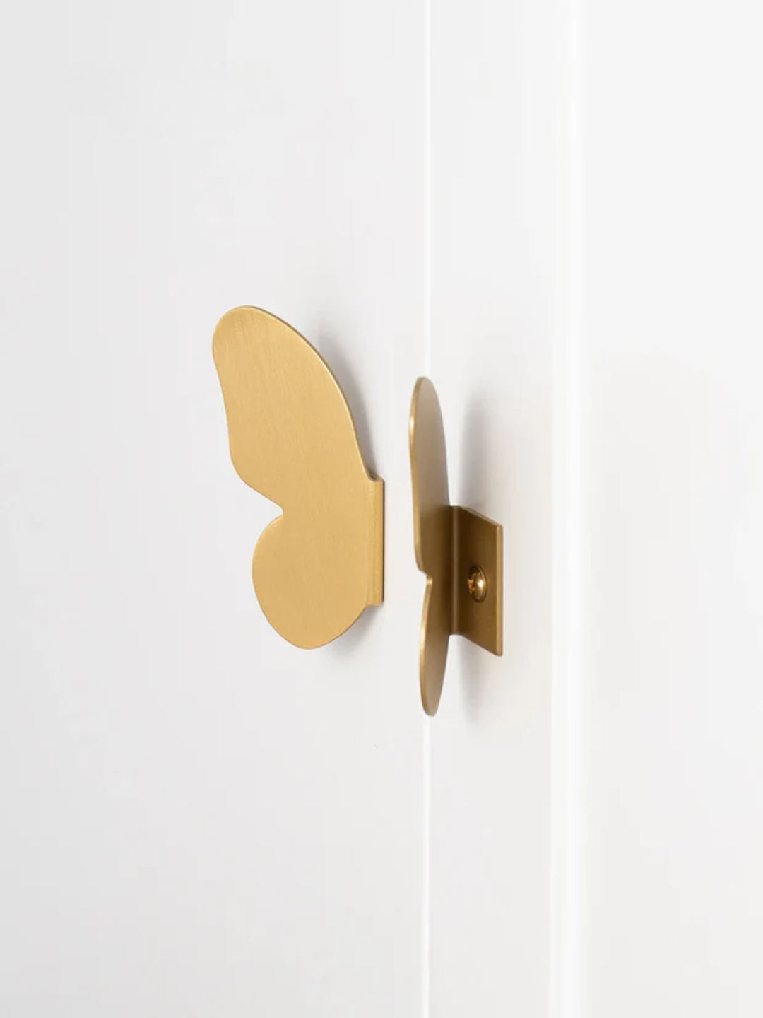 Gold butterfly-shaped wall hooks on a white background