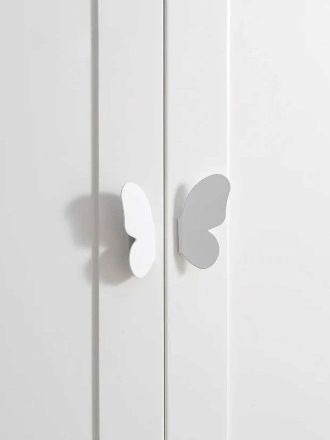 White butterfly-shaped cabinet handles on a white cabinet door.