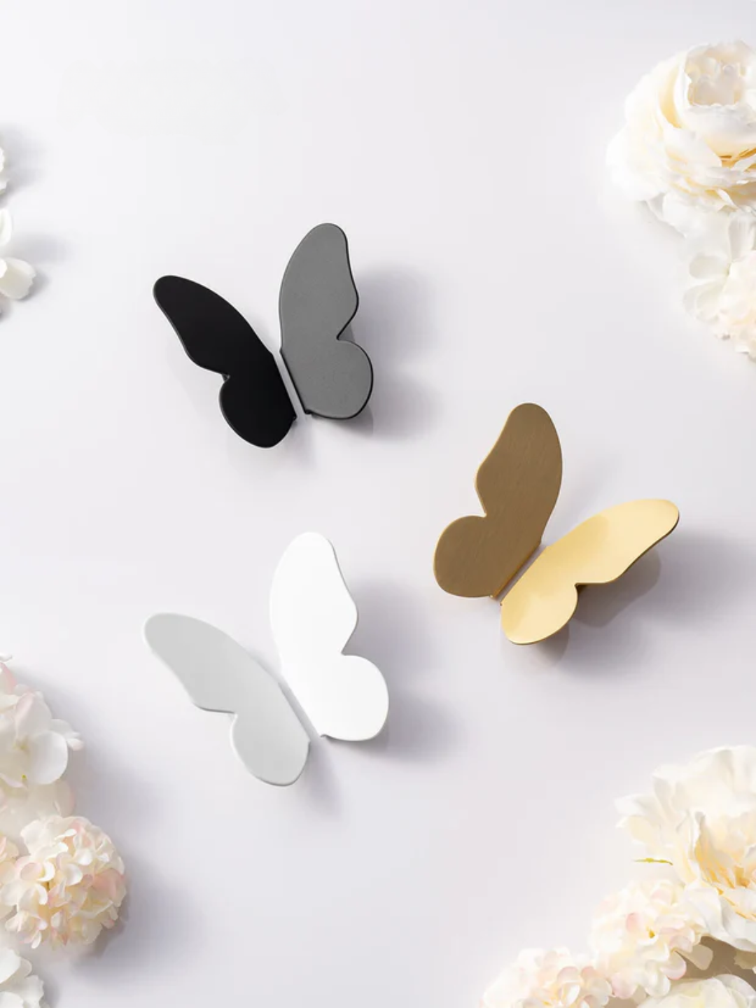 Butterfly-shaped decor items in black, gray, and gold on a light background with floral elements.