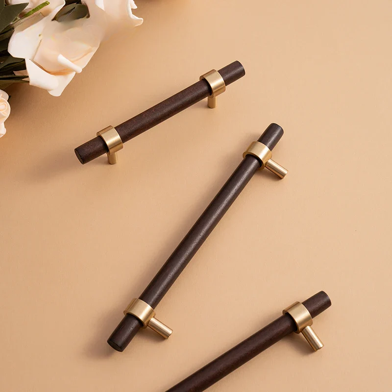 Wooden cabinet handles with gold accents on a beige surface