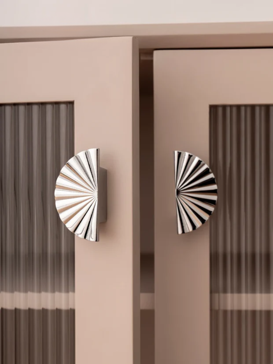 Decorative cabinet doors with sunburst pattern handles on a neutral background