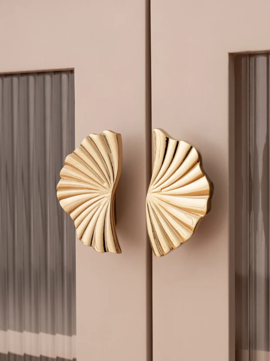 Decorative gold handles on a pink cabinet with a blurred background