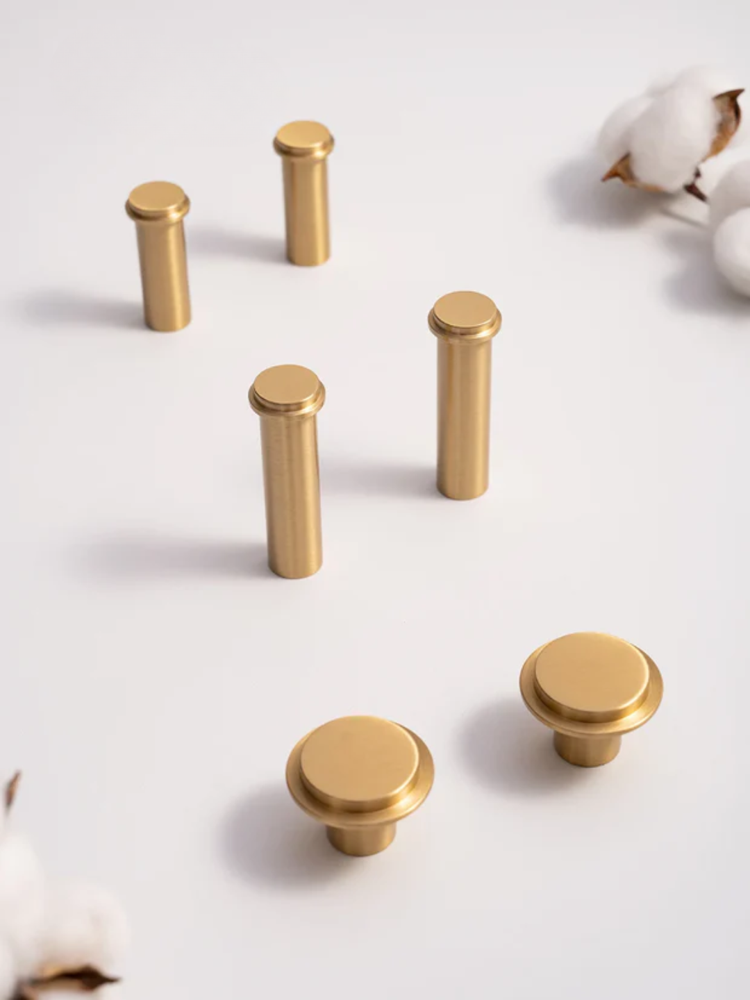 Gold cabinet knobs on a white surface with cotton flowers, featuring the Santaya brand.