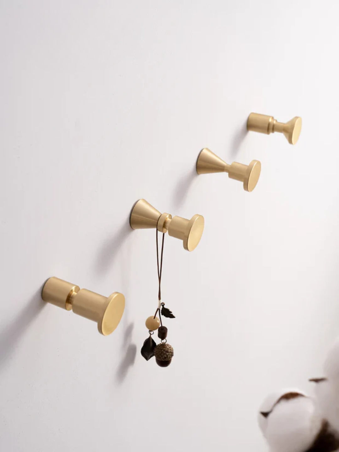Gold wall hooks with decorative items on a white wall, featuring the Santaya brand.