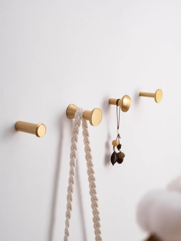 Gold wall hooks with decorative items on a white wall, featuring the Santaya brand.