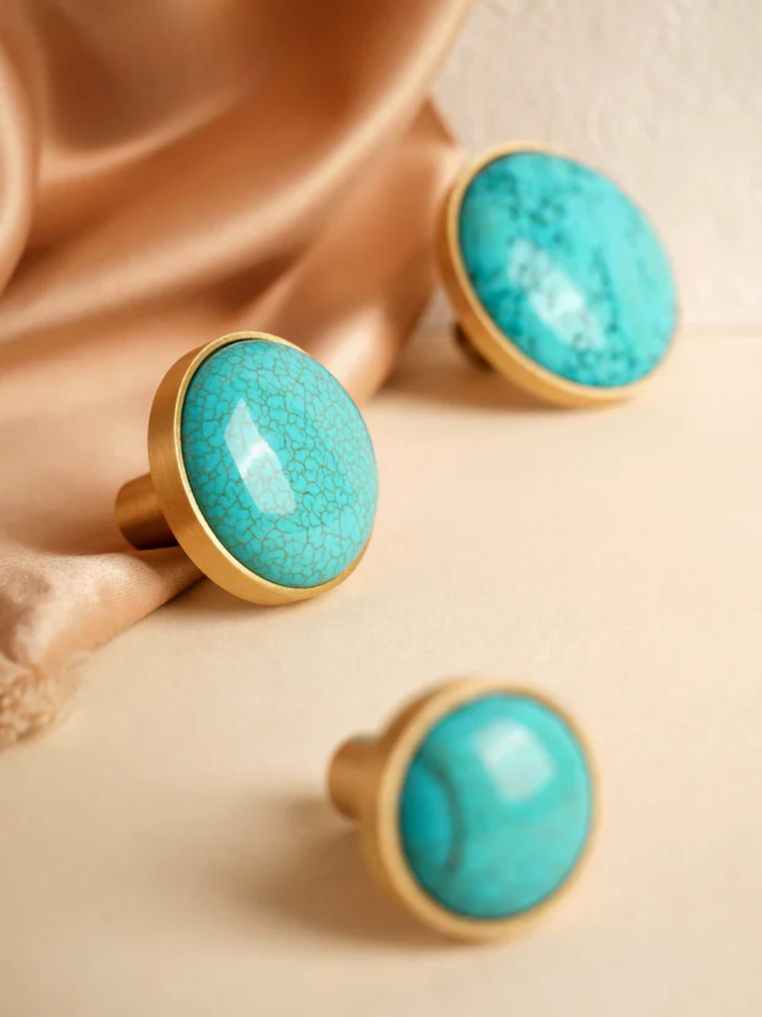 Turquoise earrings with gold bases on a beige fabric background