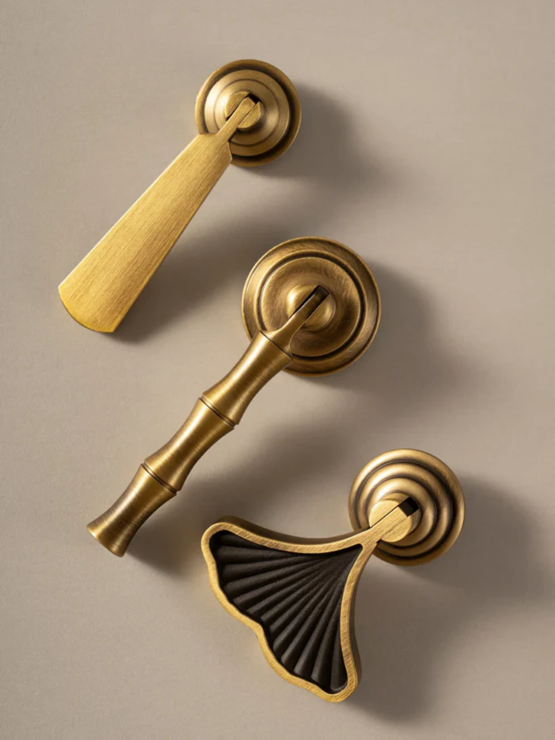 Set of gold door handles and a black decorative knob on a beige background.