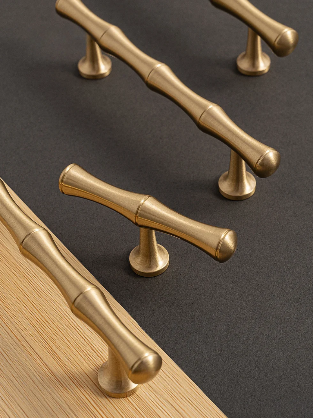 Gold cabinet handles on a dark surface and wooden surface