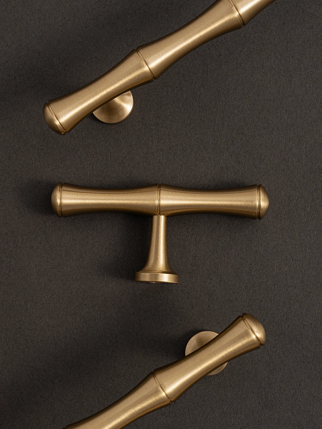 Three gold cabinet handles on a dark background